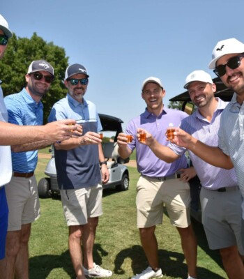 Golf tournament participants toasting on the course beside a golf cart